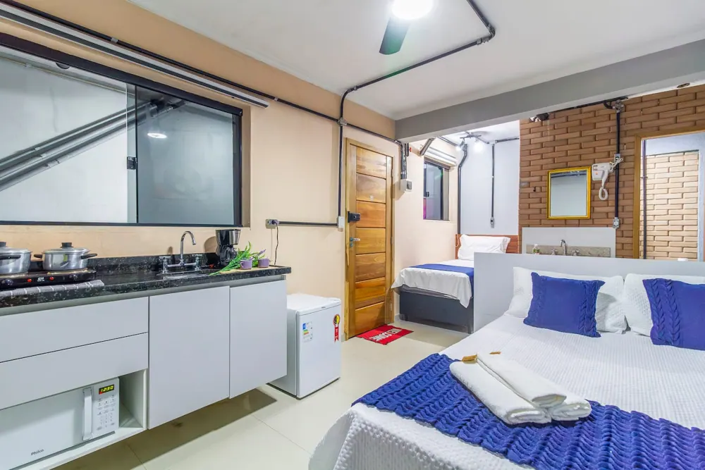 Suíte com cama de casal, cama de solteiro e cozinha compacta, em Guarulhos